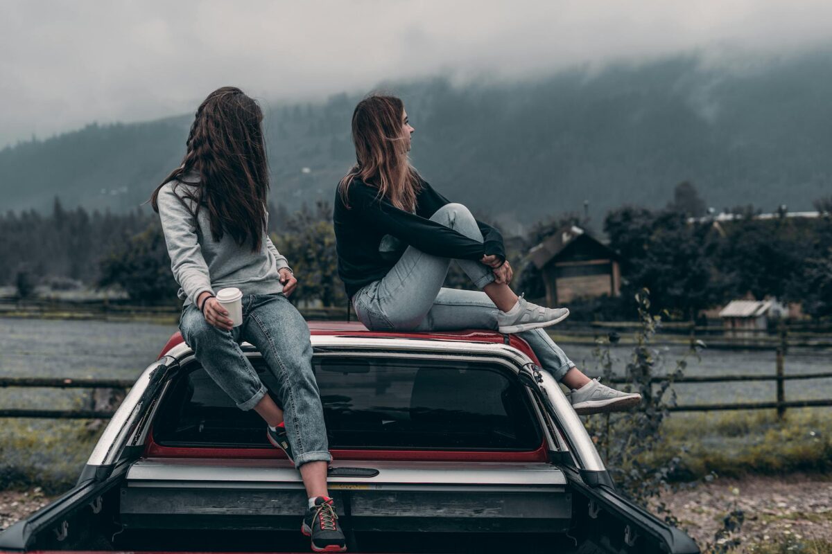 Duas jovens usando calça jeans olhando para o horizonte.